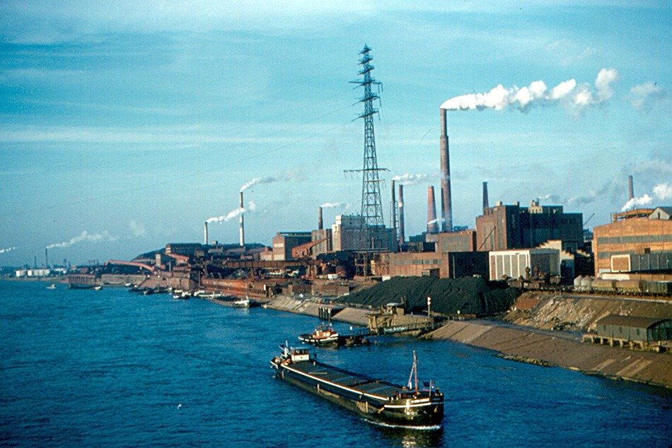 Containerschiff auf Fluß, im Hintergrund sind Schornsteine zu sehen, Kraftwerk, Himmel blau